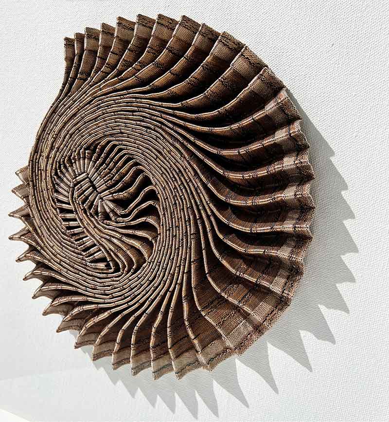 AMMONITE SHADOW: Copper Swirl | 2022 | Famed Size: 43cm x 43cm x 7cm | Materials and Techniques: Hannah White's woven fabric pleated, sculpted and hand-stitched to stretched canvas in a deep wooden frame with art glass. | Photograph: Hannah White.