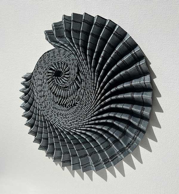 AMMONITE SHADOW: Azurite Swirl | 2022 | Framed Size: 53cm x 53cm x 7cm | Materials and Techniques: Hannah White's woven fabric pleated, sculpted and hand-stitched to stretched canvas in a deep wooden frame with art glass. | Photograph: Hannah White.